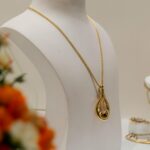 Elegant gold necklace showcased on a bust in a luxury setting with soft lighting.